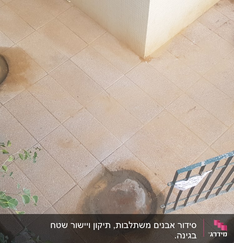 שני חורים ברצפת אריחים ליד גדר מתכת